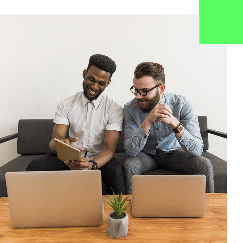 Deux hommes en pleine collaboration, assis autour d'une tablette et d'ordinateurs dans l'équipe AGITEX.