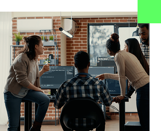 "Réunion professionnelle dans le domaine de l'IT : Plusieurs experts, dont un développeur de logiciel, engagés dans une discussion autour d'un ordinateur où du code est affiché à l'écran.