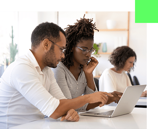 Photo représentant un expert technique du secteur numérique formant sur un ordinateur une jeune apprentie en transformation numérique.